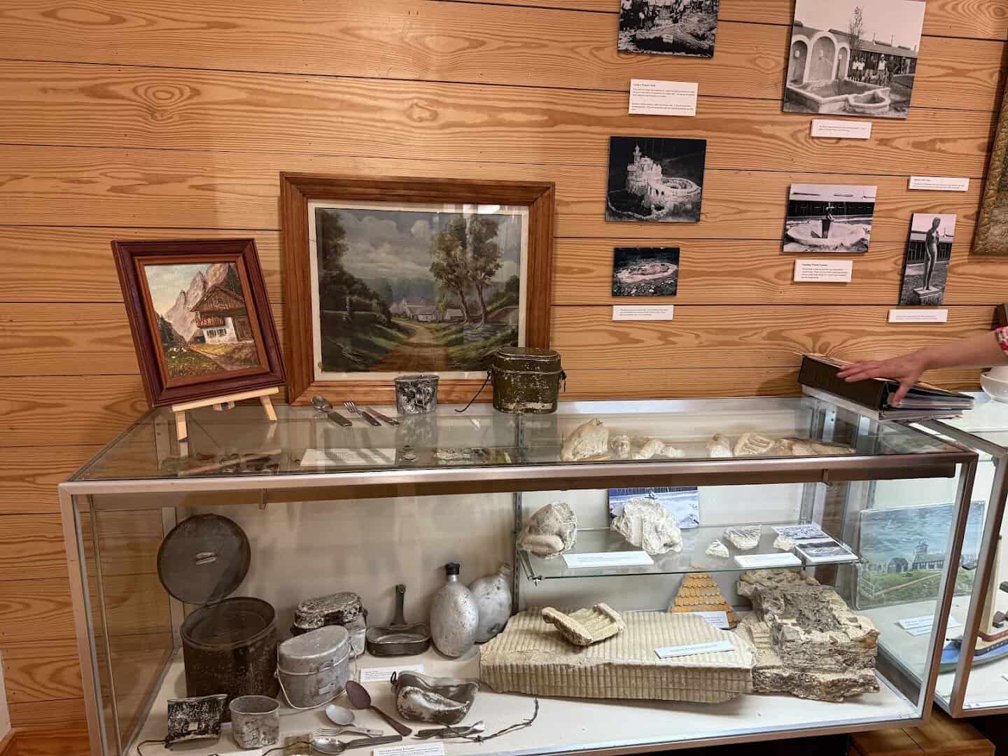 Display case of excavated canteens, mess kits and prisoner paintings at Camp Hearne