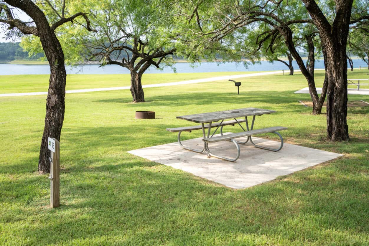 Campsite picnic table under oak trees beside Lake Travis at Muleshoe Bend