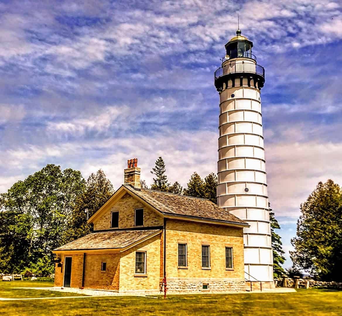 The white Cana Island Lighthouse tower and stone keeper's house under a blue sky in Door County, Wisconsin