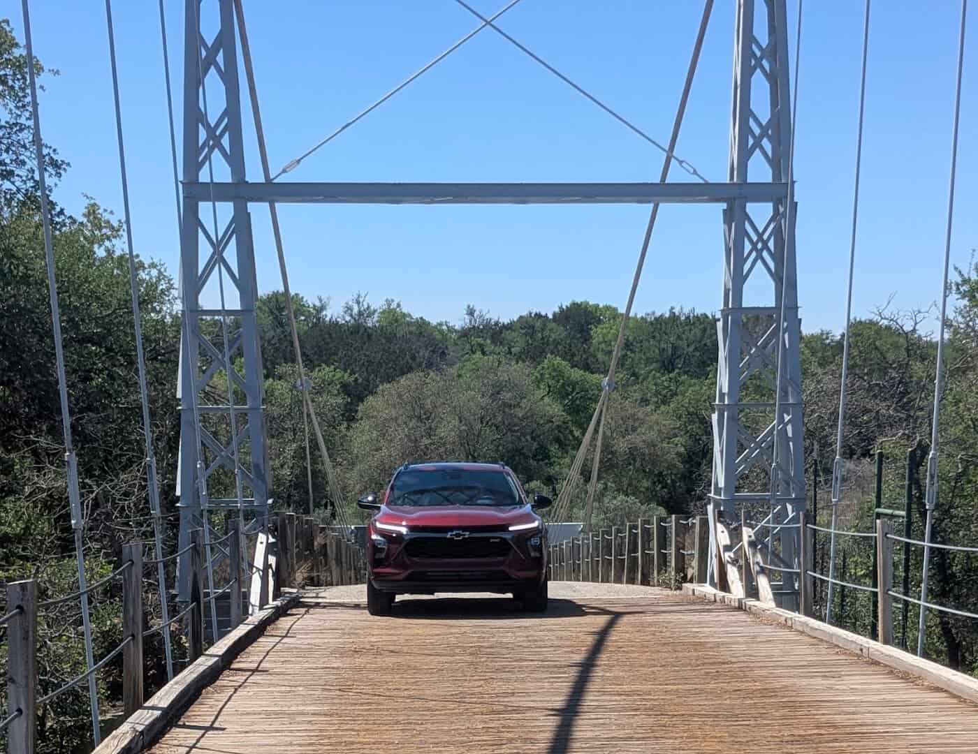 A car crossing the one-lane Regency Suspension Bridge over the Colorado River in Texas