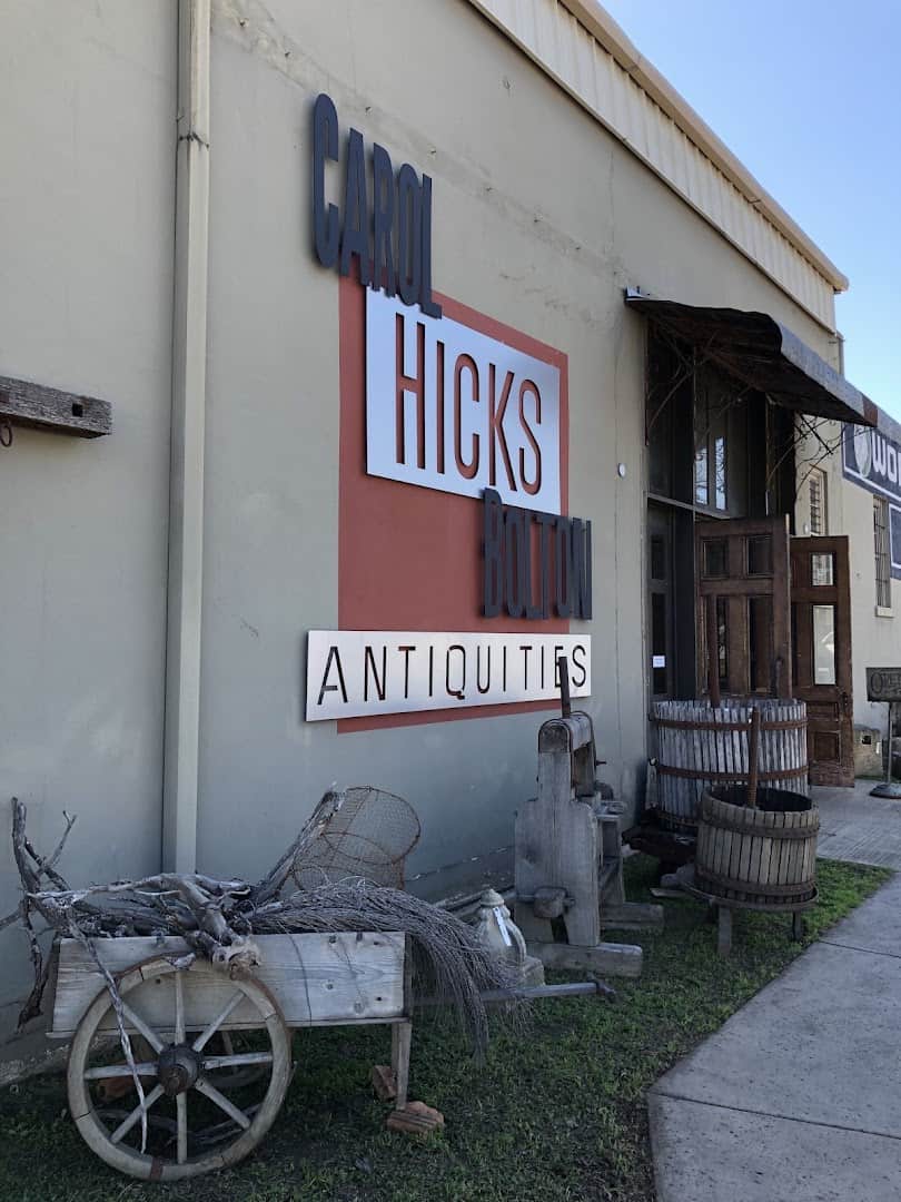 Carol Hicks Bolton Antiquities sign on the warehouse front with an old wooden cart on Lincoln Street in Fredericksburg