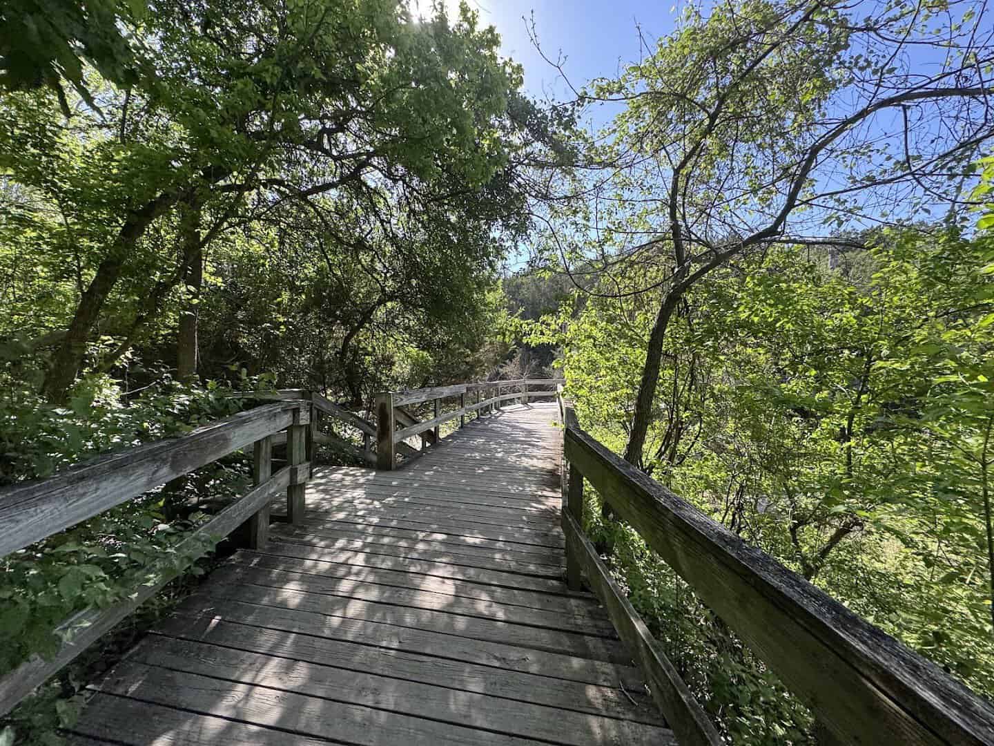 Shaded wooden boardwalk trail winding through trees at Chalk Ridge Falls Park near Belton, Texas