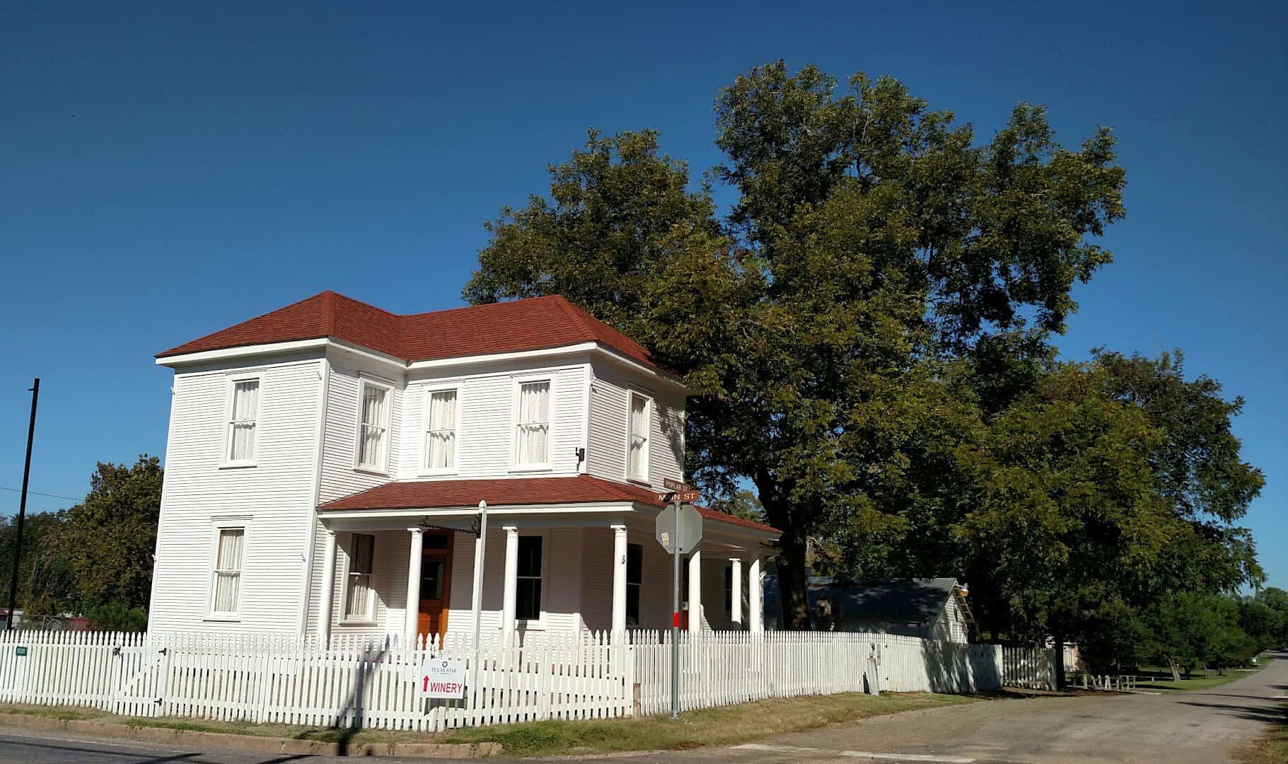 Historic two-story white house shaded by oaks in Chappell Hill, Texas