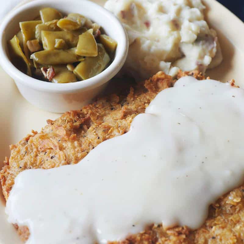 Chicken fried steak under homemade cream gravy with mashed potatoes and green beans at Hill Country Cupboard