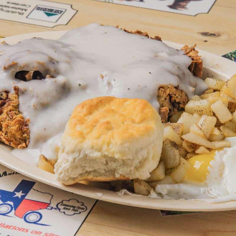 Chicken fried steak smothered in creamy homemade country gravy with a biscuit at Hill Country Cupboard