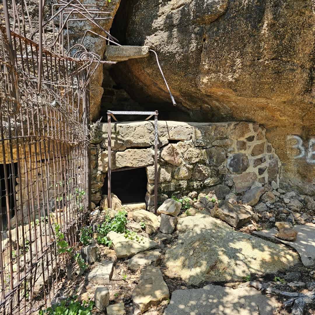 Old stone animal enclosure with a rusted wire cage built into the rock at the abandoned Cisco zoo