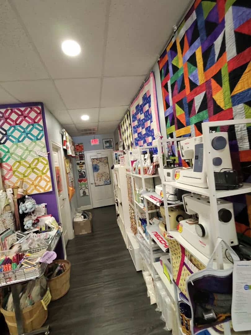 Colorful quilts and fabric on display inside The Sparkly Elephant Sewing Lounge in Friendswood, Texas