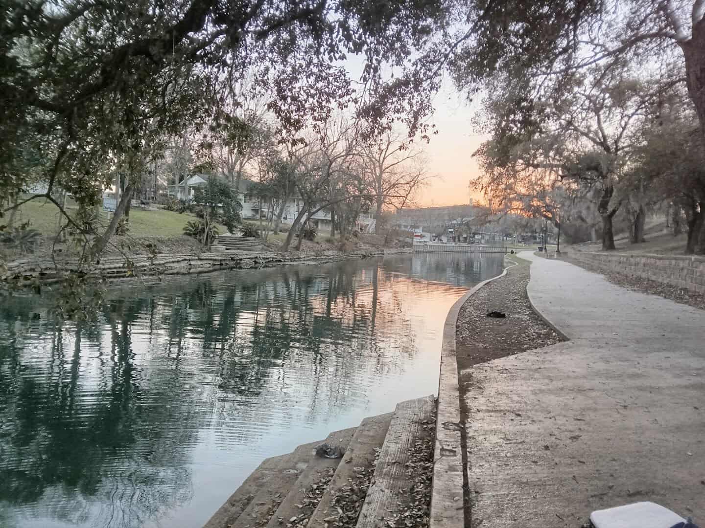 Golden dawn light reflecting on the calm Comal River at Hinman Island Park