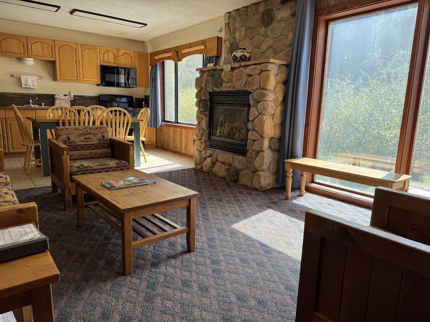 Cozy cabin interior with a stone fireplace and forest window, Copper King Lodge, Red River, New Mexico