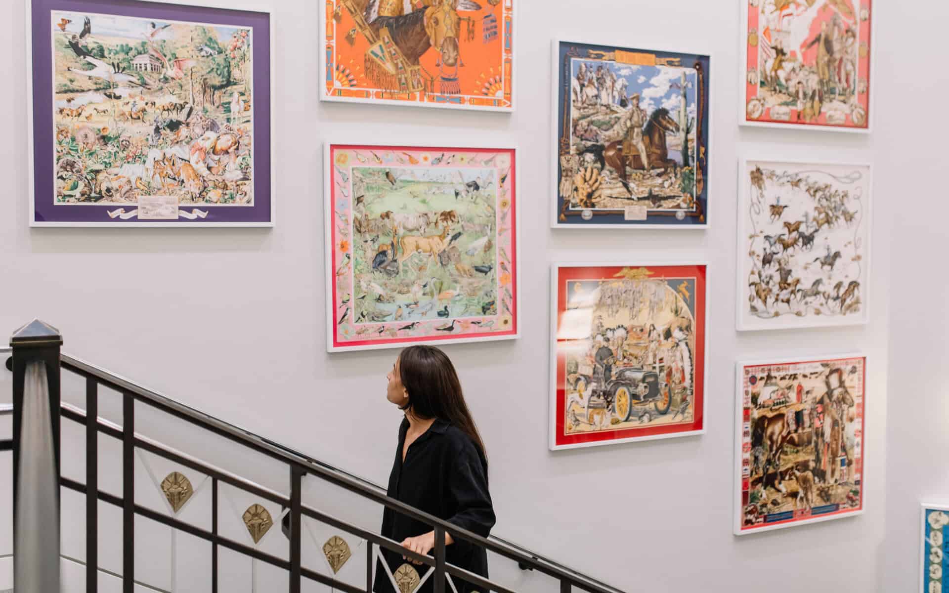 Wall of colorful Western-themed artwork on a staircase at the National Cowgirl Museum