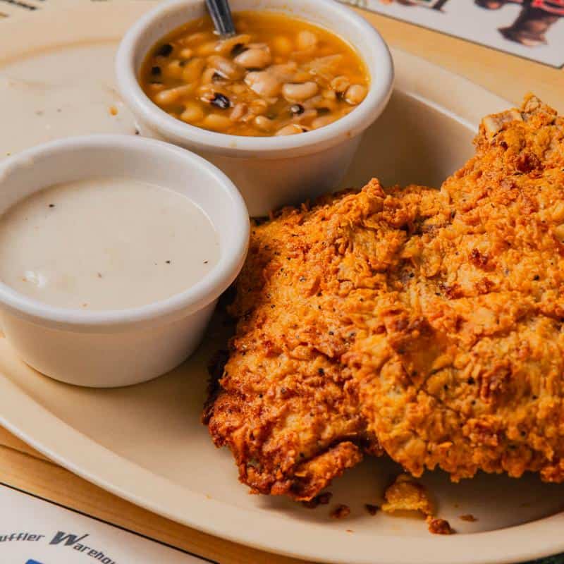 Crispy hand-battered chicken fried steak with a cup of cream gravy at Hill Country Cupboard