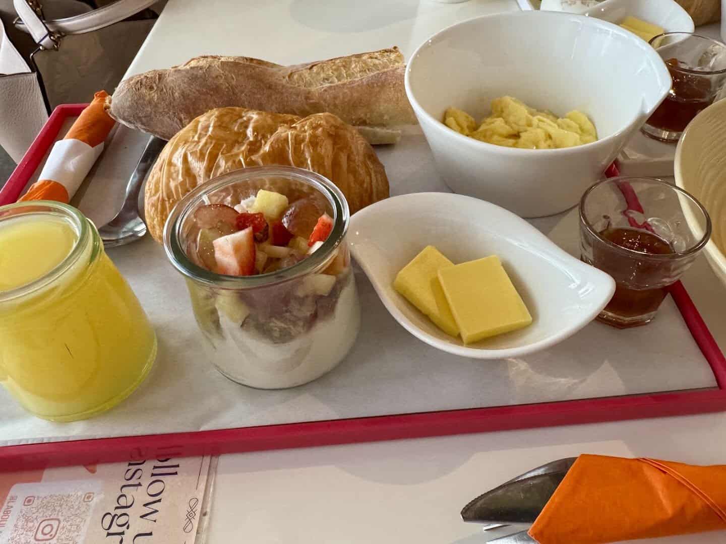 Fresh croissant with orange juice and fruit on a breakfast tray at La Boulangerie in San Antonio