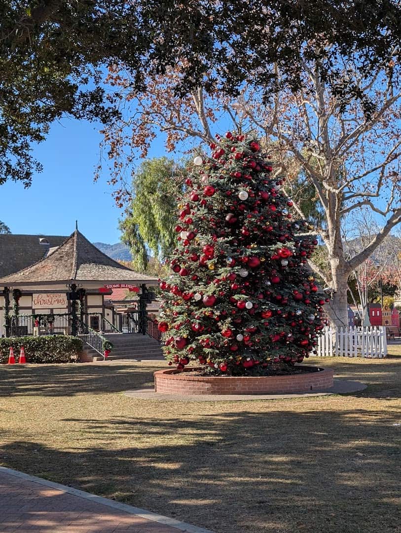 Red-ornamented Christmas tree in Solvang Park framed by half-timbered Danish architecture in Solvang, California