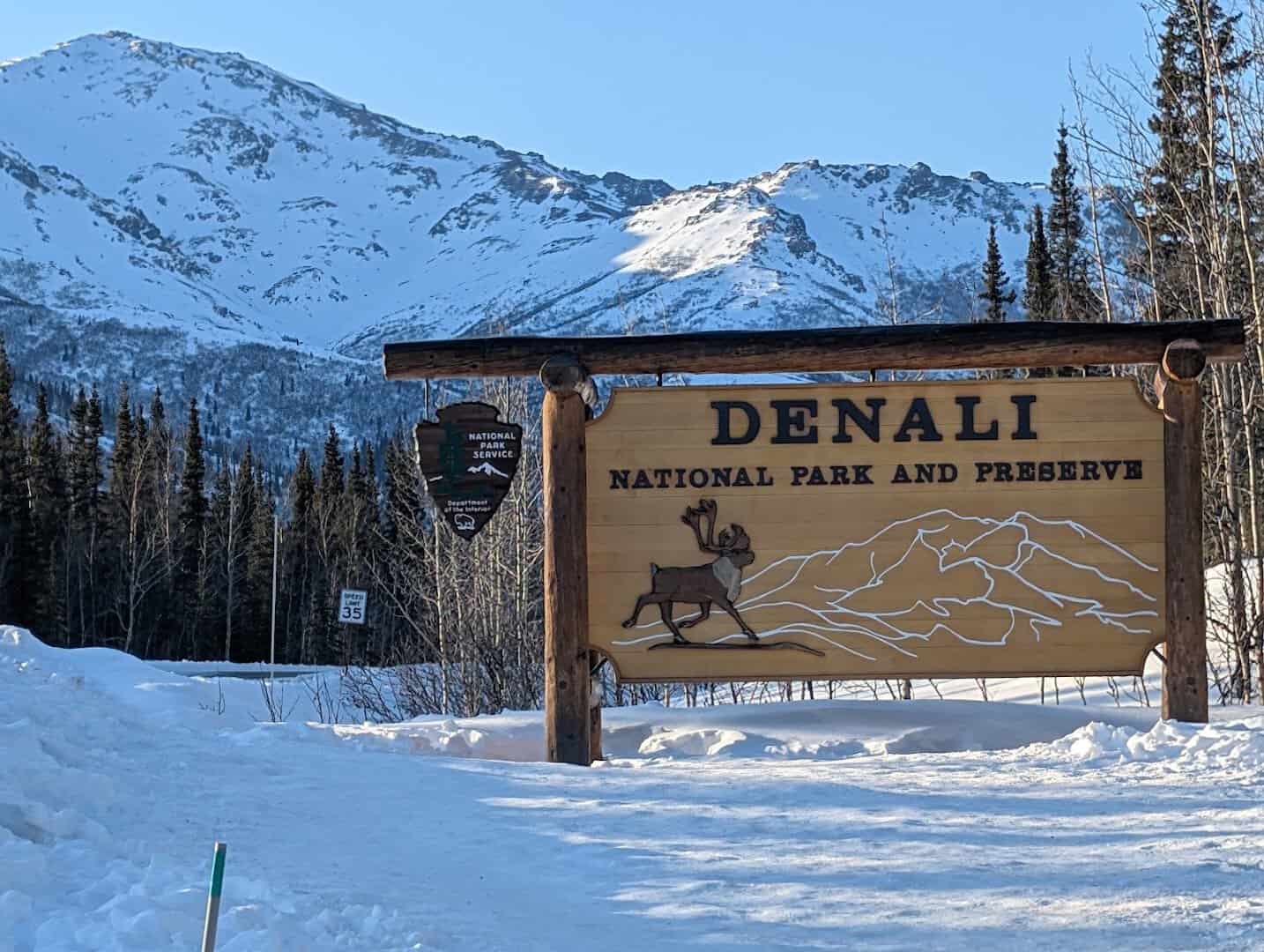 Snowy peaks behind the Denali National Park and Preserve entrance sign, Alaska