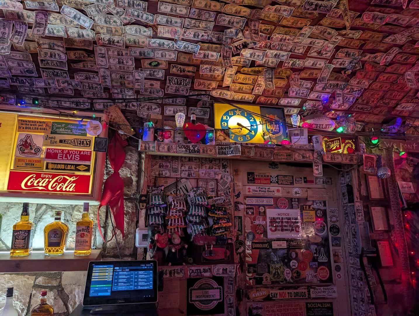 The bar, liquor shelf and dollar-bill ceiling inside Devil's Backbone Tavern in Fischer, Texas