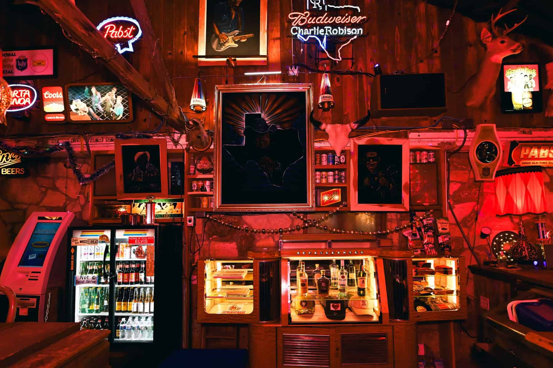 Jukebox, neon beer signs and framed portraits inside Devil's Backbone Tavern in Fischer, Texas