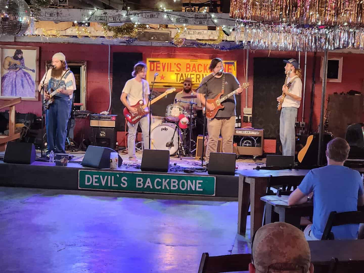 A band playing live music under the Devil's Backbone Tavern sign in Fischer, Texas