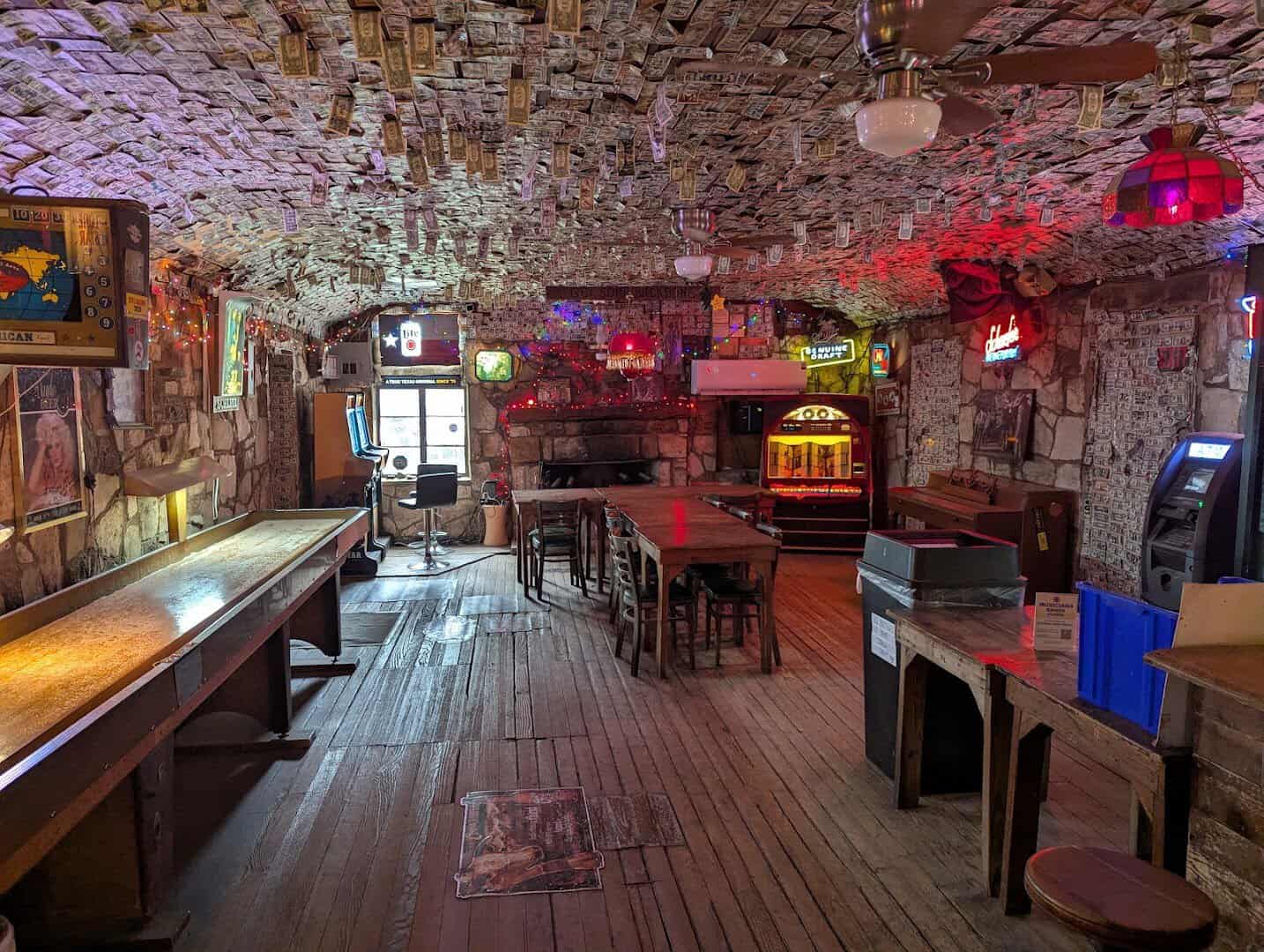 The main room with a shuffleboard table, jukebox and dollar-bill ceiling at Devil's Backbone Tavern in Fischer, Texas