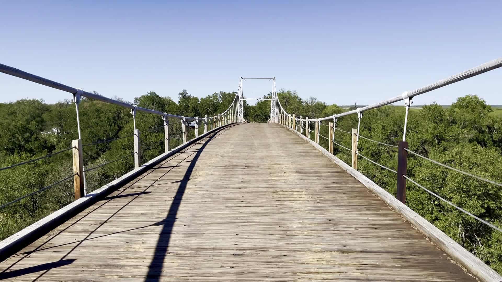 Driving across the wooden plank deck of the Regency Suspension Bridge in Texas