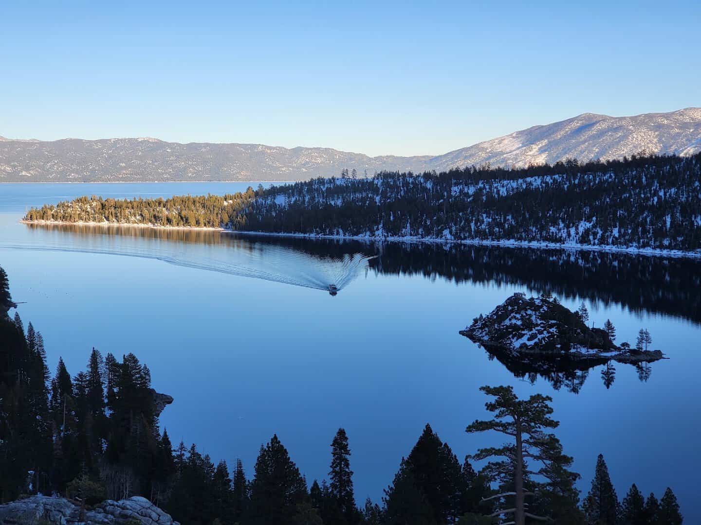 Snow-dusted shoreline and Fannette Island in the blue water of Emerald Bay, Lake Tahoe, California