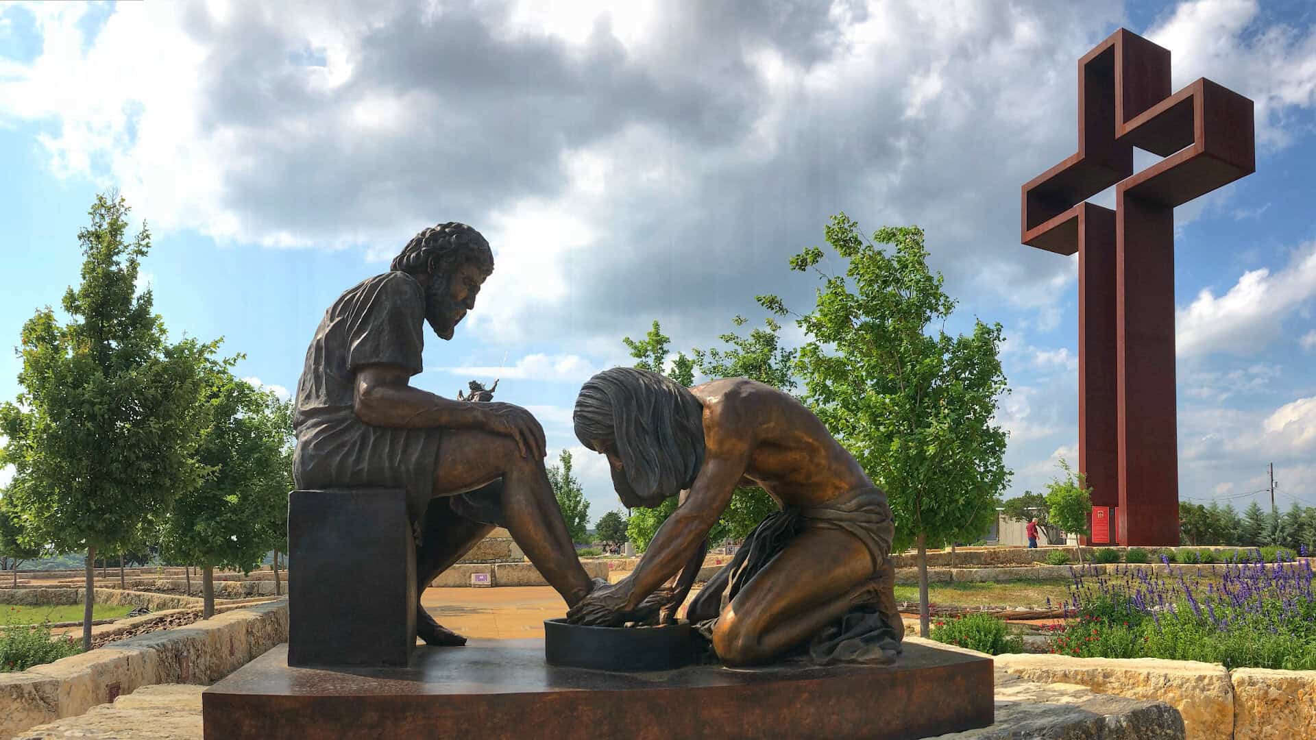 The Empty Cross standing above the Divine Servant sculpture at the Coming King Sculpture Prayer Garden