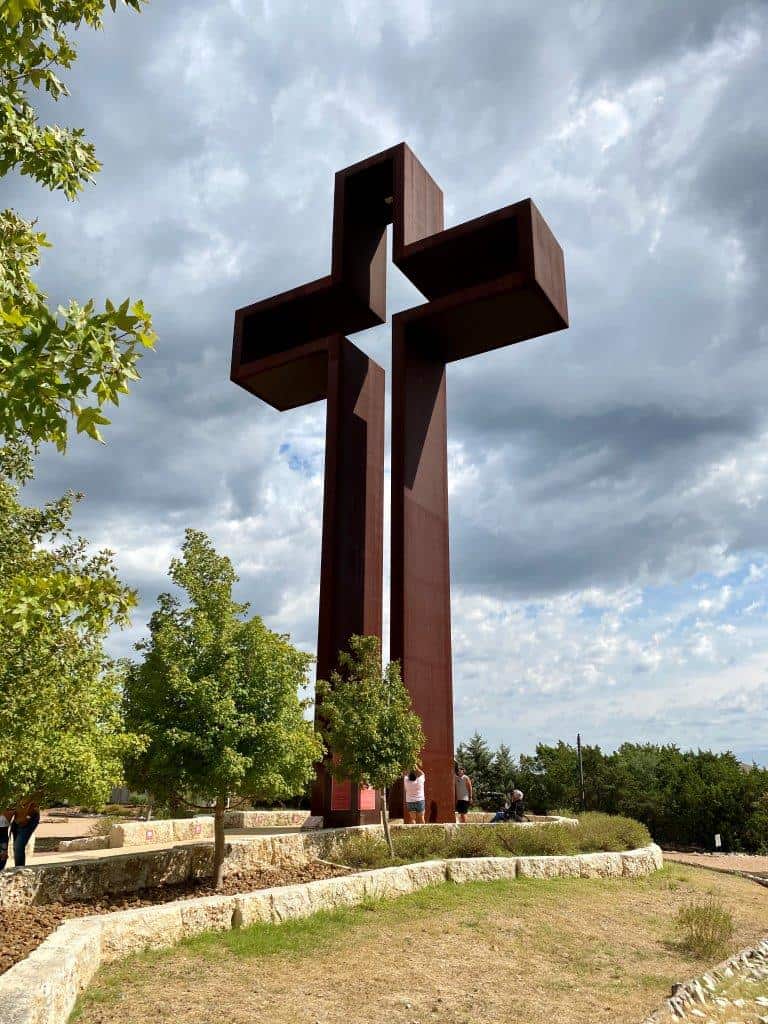 The 77 foot Empty Cross against a cloudy sky at the Coming King Sculpture Prayer Garden