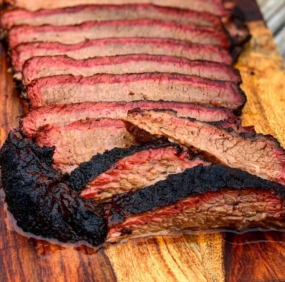 Sliced smoked brisket on a wood board at Feral Smoke and Fire in Kerrville, Texas