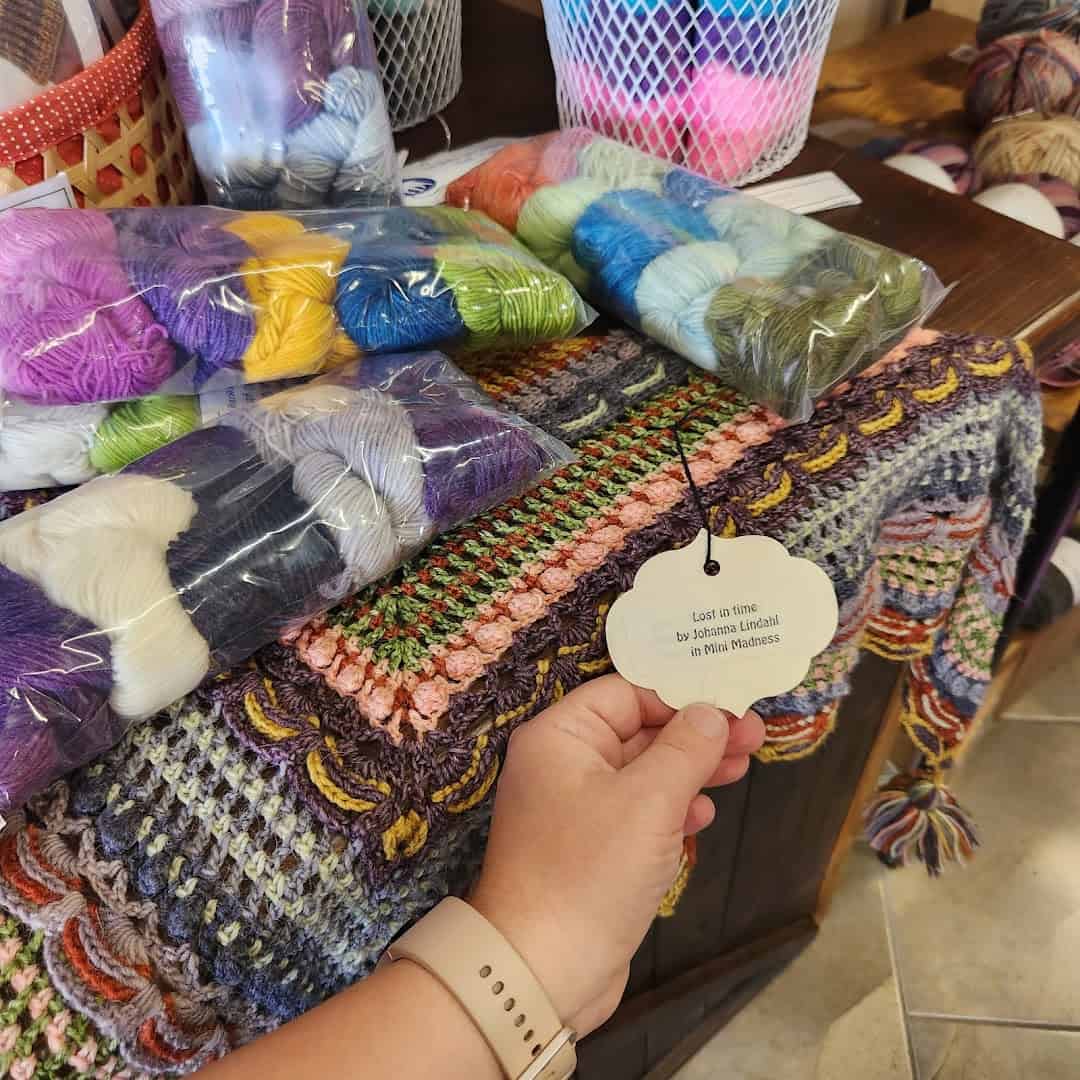 A finished crochet shawl on display with yarn kits at Lone Star Yarn in Bedford, Texas