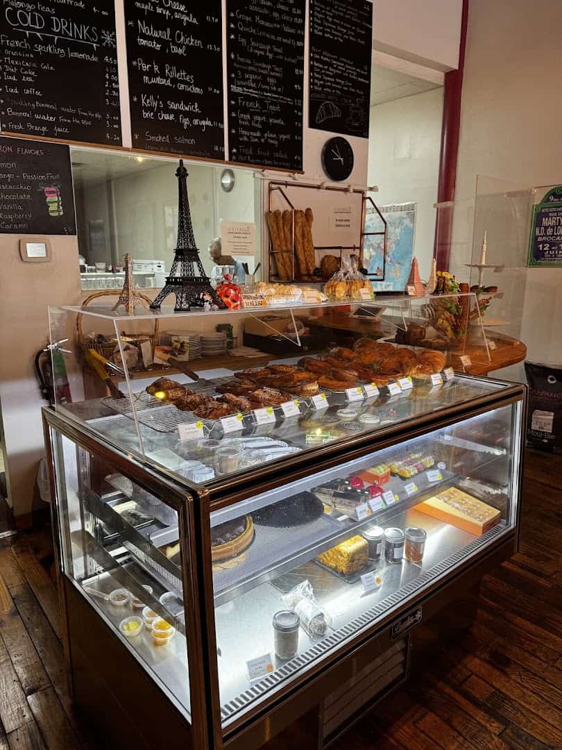 Pastry display case with a small Eiffel Tower and French chalkboard at La Boulangerie in San Antonio