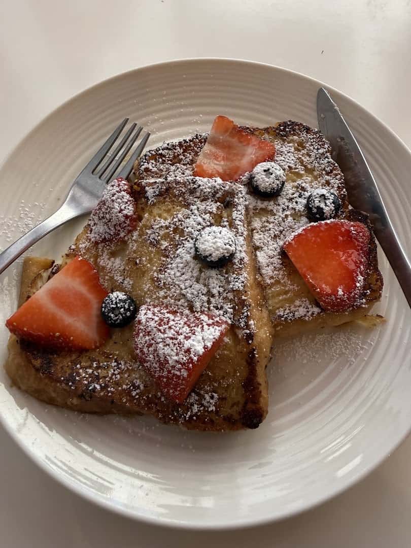 French toast dusted with powdered sugar and topped with fresh berries at La Boulangerie in San Antonio