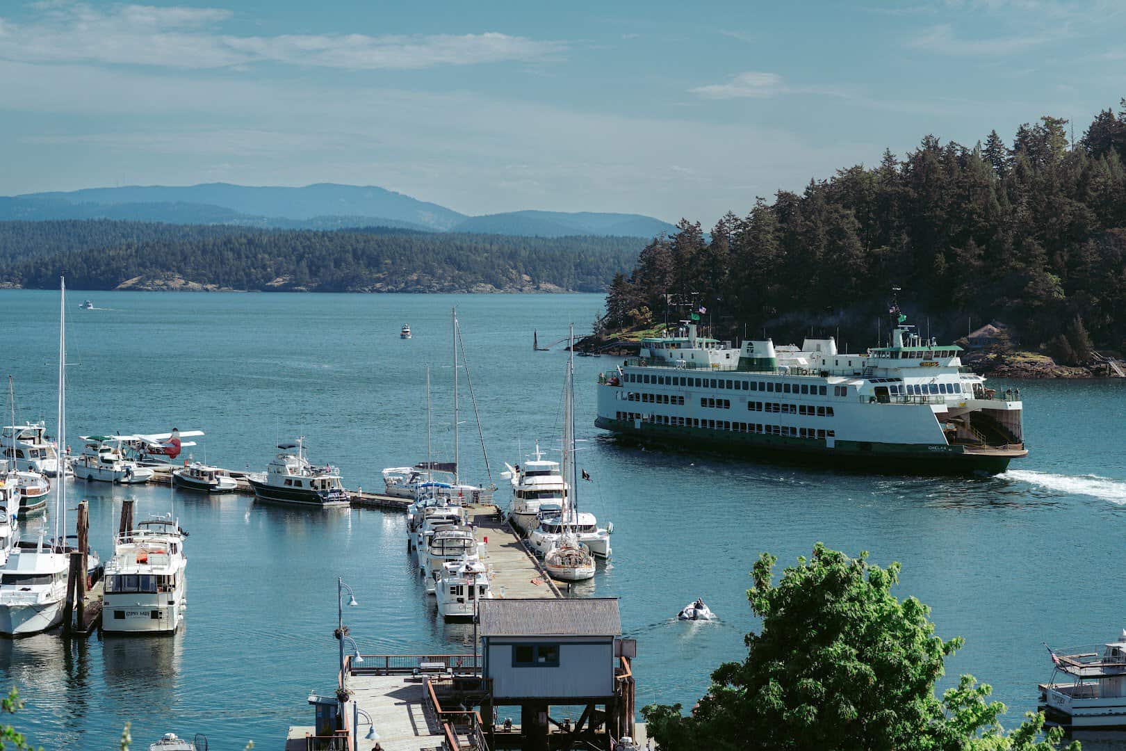 Boats and a ferry in the harbor with green islands beyond at Friday Harbor in the San Juan Islands, Washington