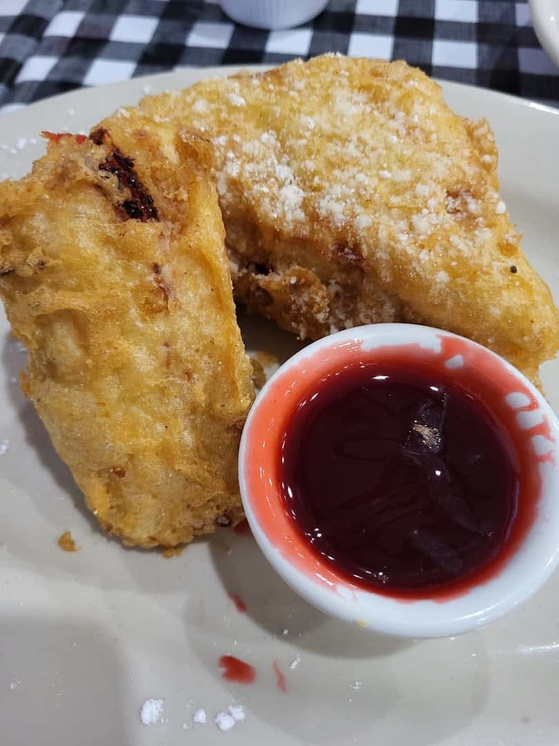 Powdered sugar fried dessert with raspberry sauce at Mels Country Cafe in Tomball, Texas