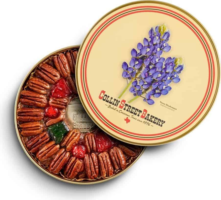 Collin Street Bakery DeLuxe fruitcake beside its keepsake gift tin