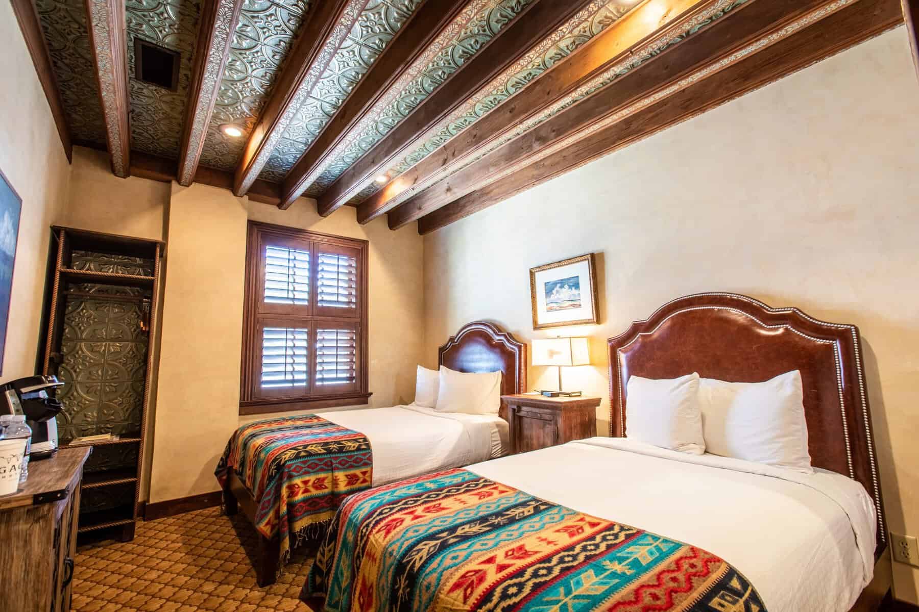 Los Portales guest room with two beds and viga ceiling at the Gage Hotel