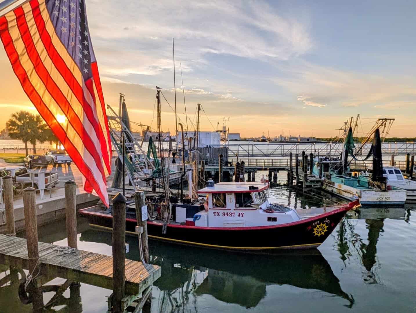Shrimp boats and an American flag at sunset on the Galveston harbor by Katie's Seafood House