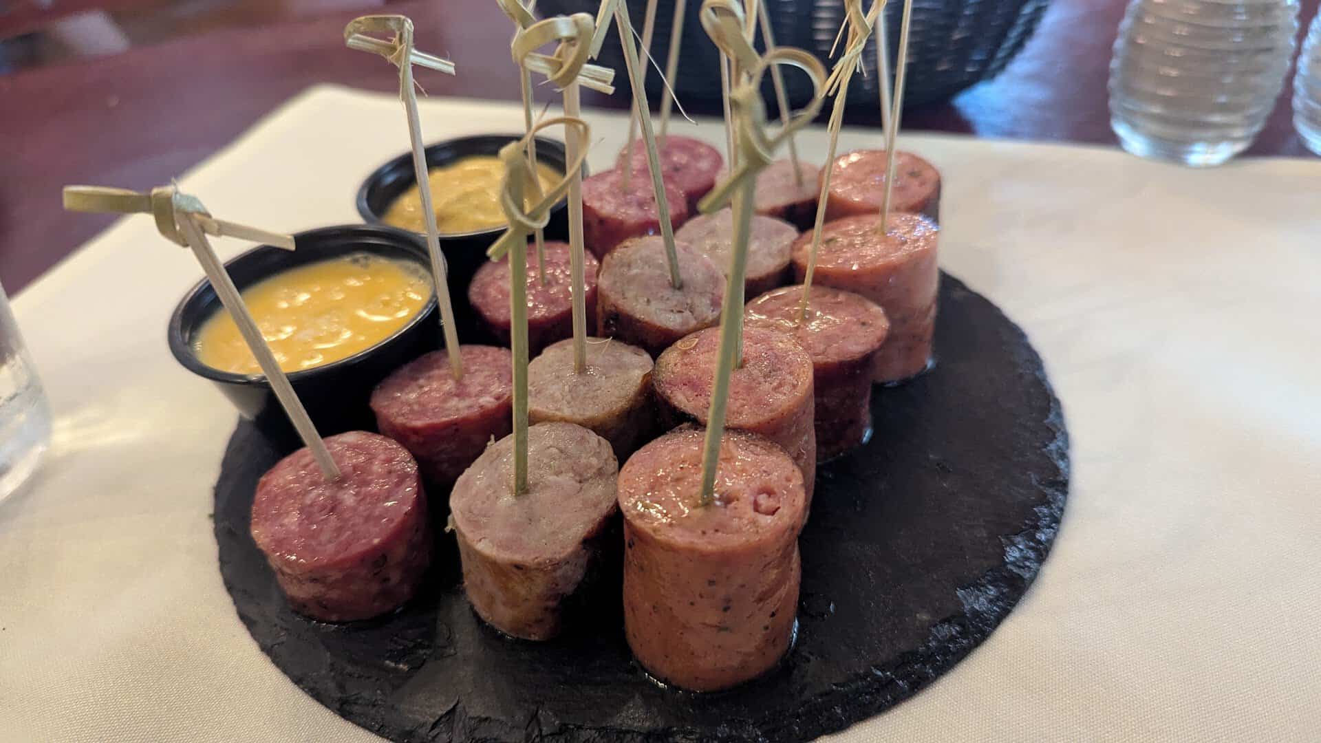 German sausage sampler on a slate board with mustard and cheese sauce at Alpine Haus in New Braunfels, Texas