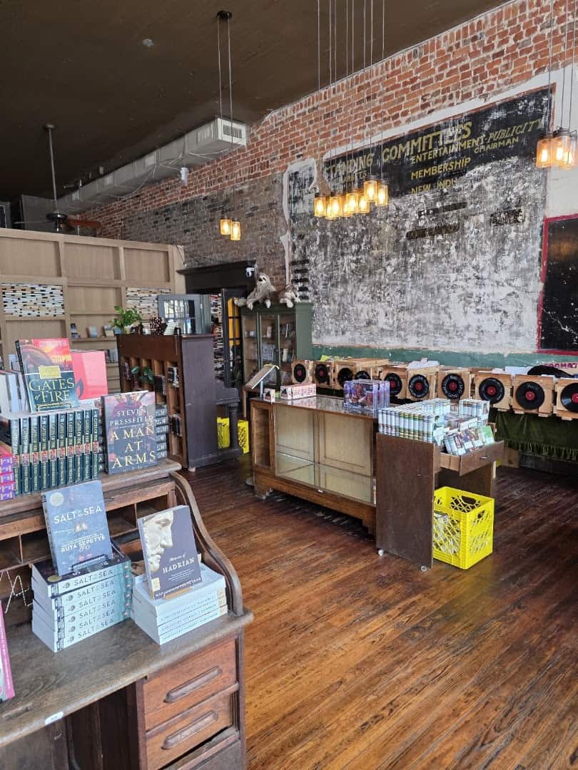 Historic ghost-sign wall and antique desk with book displays inside The Painted Porch Bookshop in Bastrop, Texas