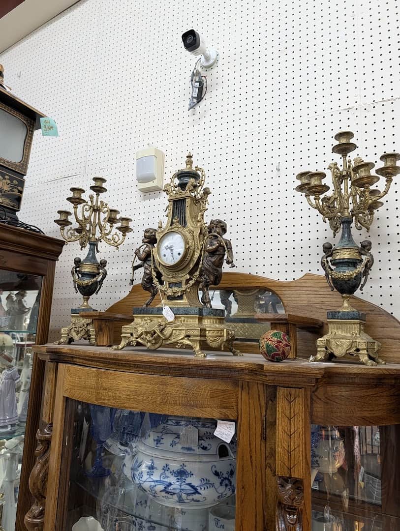 Gilt mantel clock and candelabra set on a display case at The Antique Gallery of Houston in Spring Texas