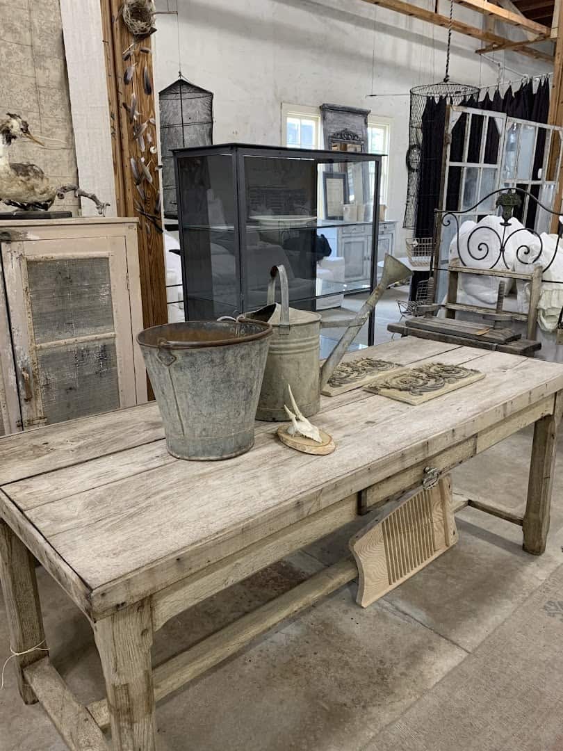 Glass display cabinets, a worn farm table and iron pails inside Carol Hicks Bolton Antiques in Fredericksburg