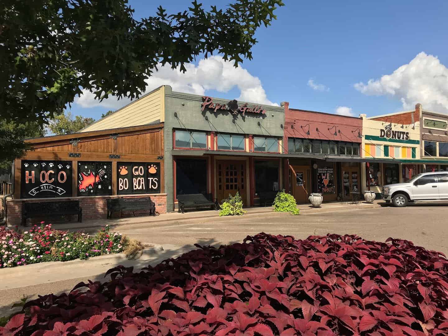 A downtown Celina storefront with a Go Bobcats sign and red flower beds