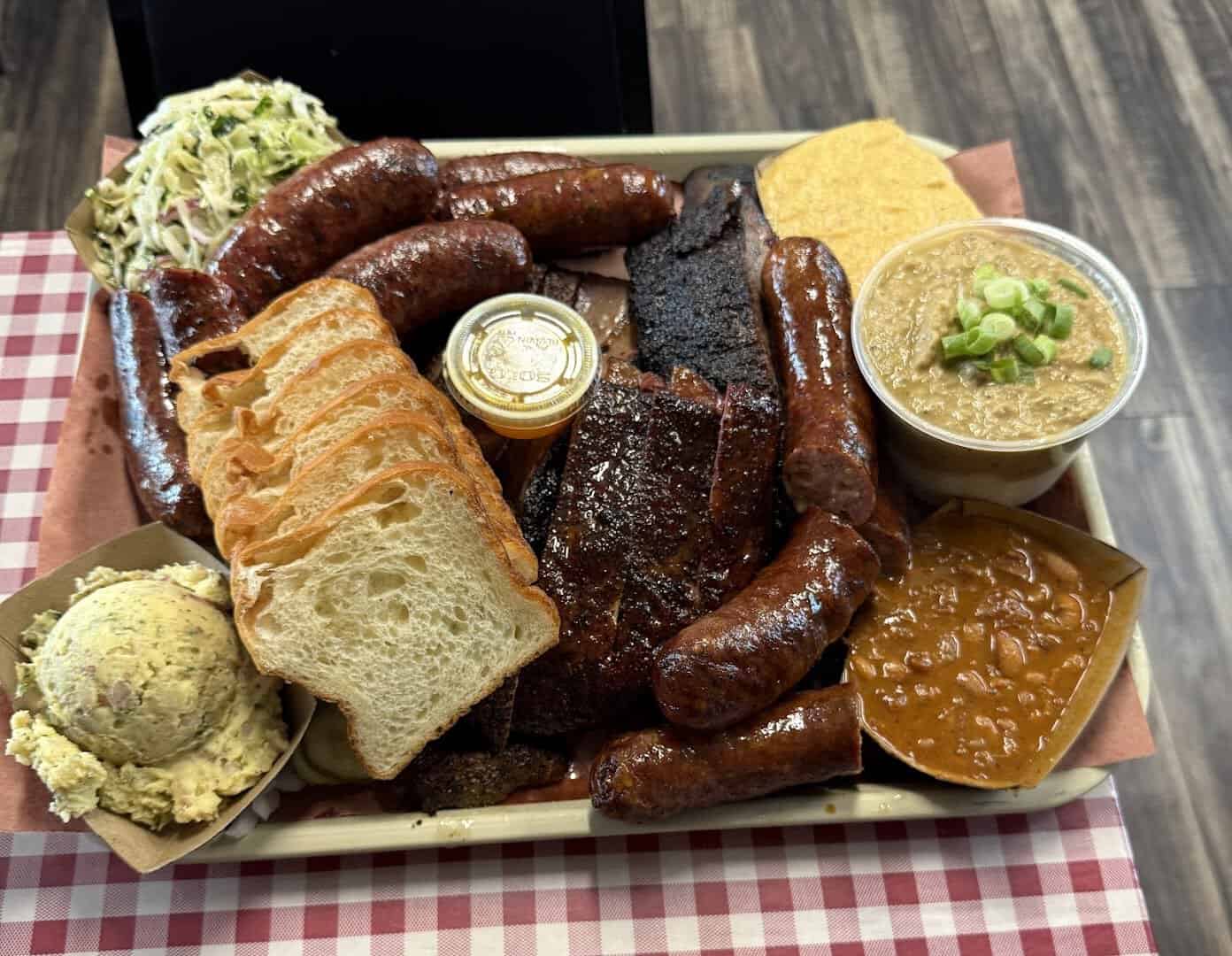 Smoked sausage, brisket and sides on a tray at Goldee's Barbecue in Fort Worth, Texas