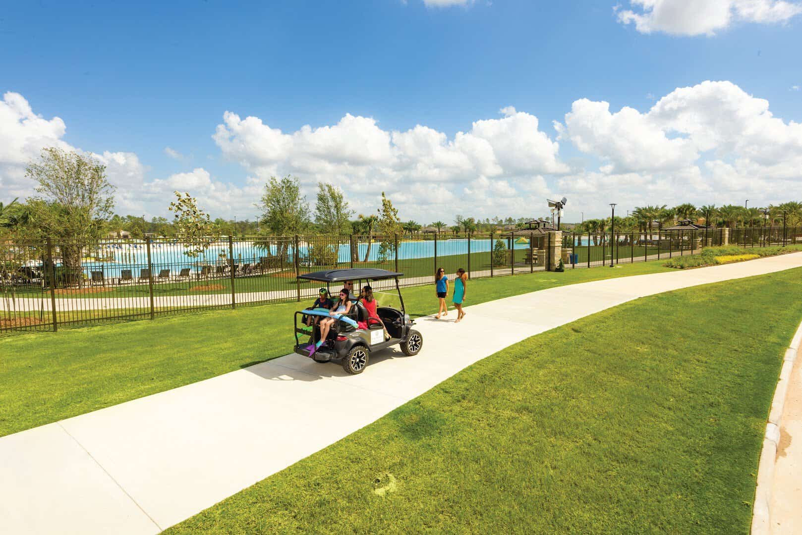A golf cart on the path beside the turquoise Crystal Lagoon at Lago Mar