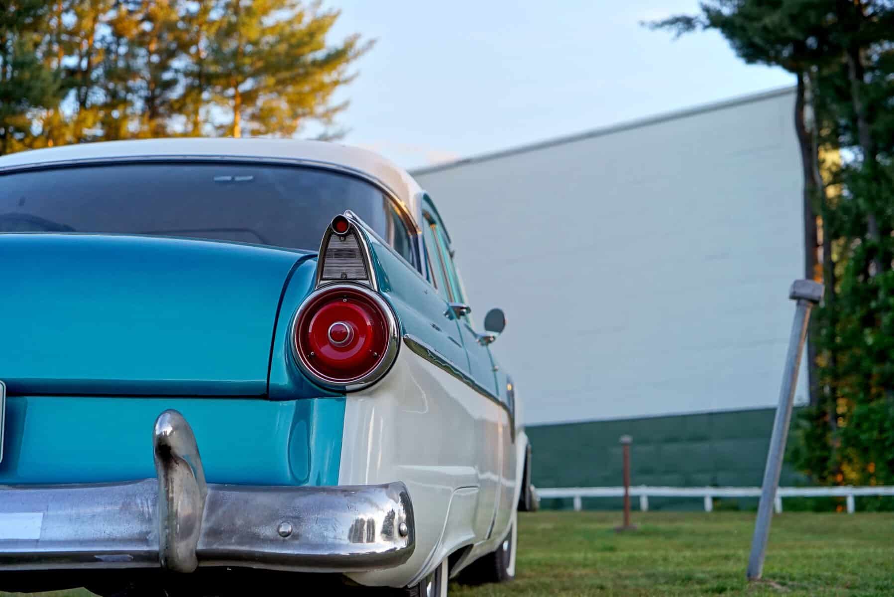 A classic car parked below the giant screen at Graham Drive-In Theatre in Graham, Texas
