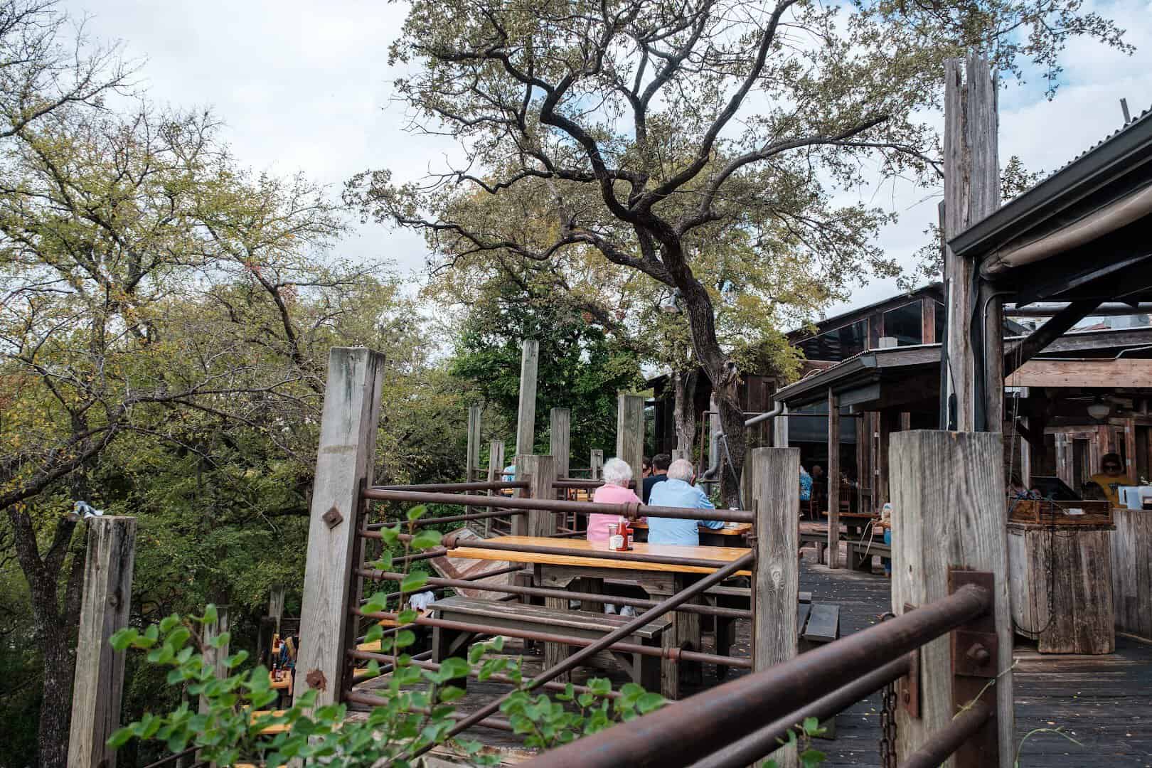 Wooded grounds and dining decks above the Guadalupe River at the Gristmill
