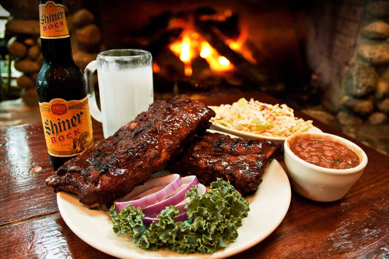 Plate of ribs with sides by the fireplace at the Gristmill River Restaurant