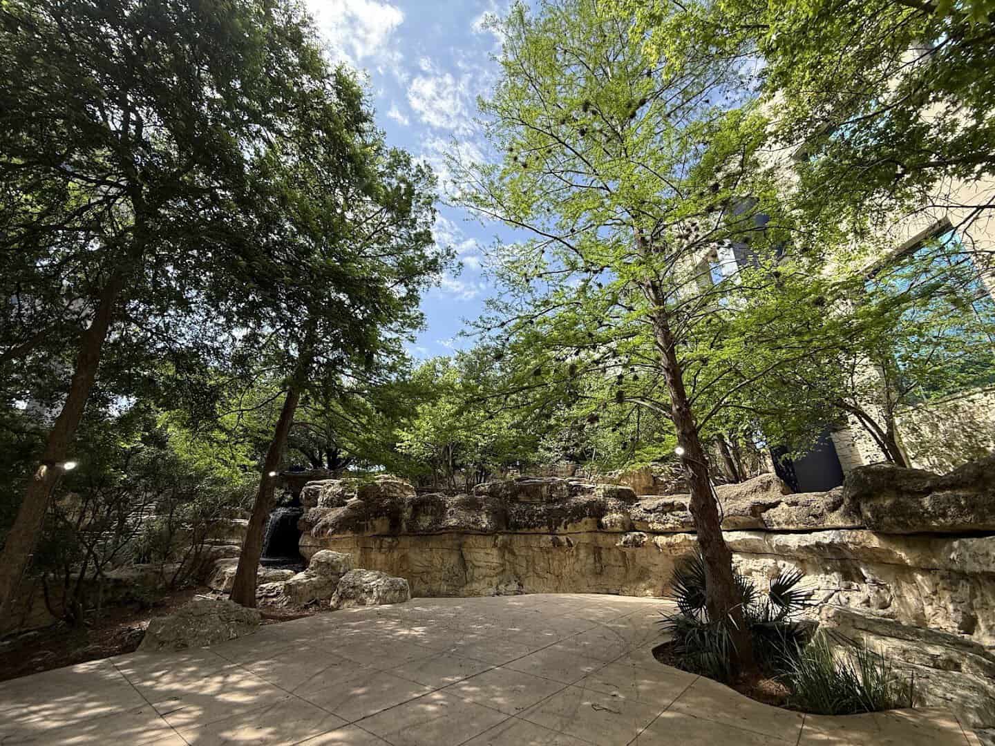 Faux bois rock walls and a waterfall in the shaded plaza at The Grotto in San Antonio