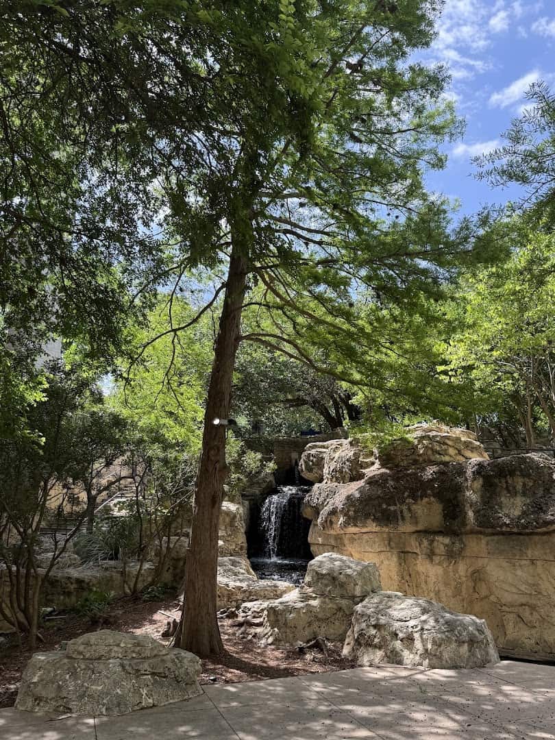 Waterfall and log-shaped concrete bench in the carved rockwork of The Grotto in San Antonio