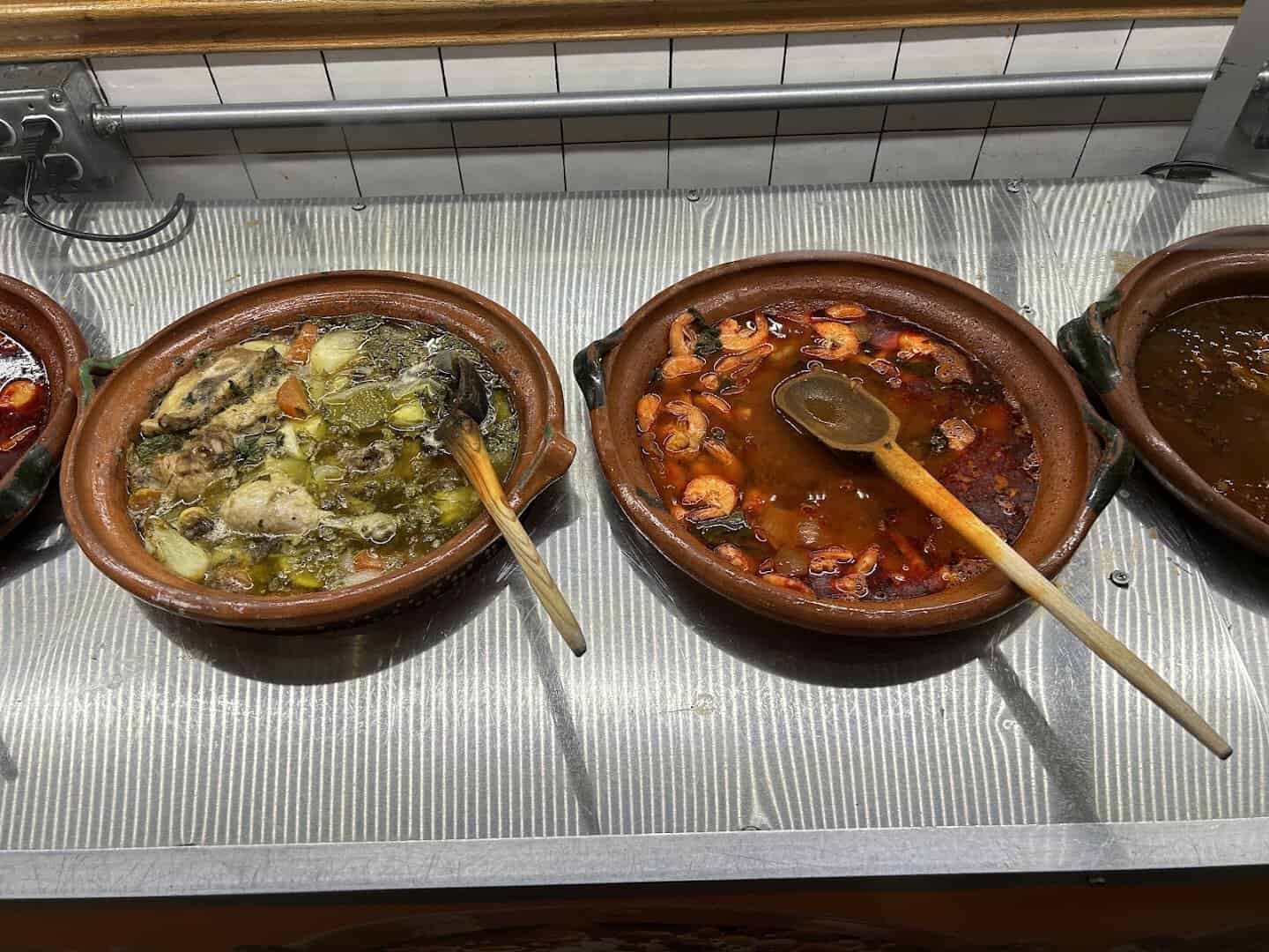 Slow-cooked guisados and stews in clay pots at Ranchero King Buffet in Houston