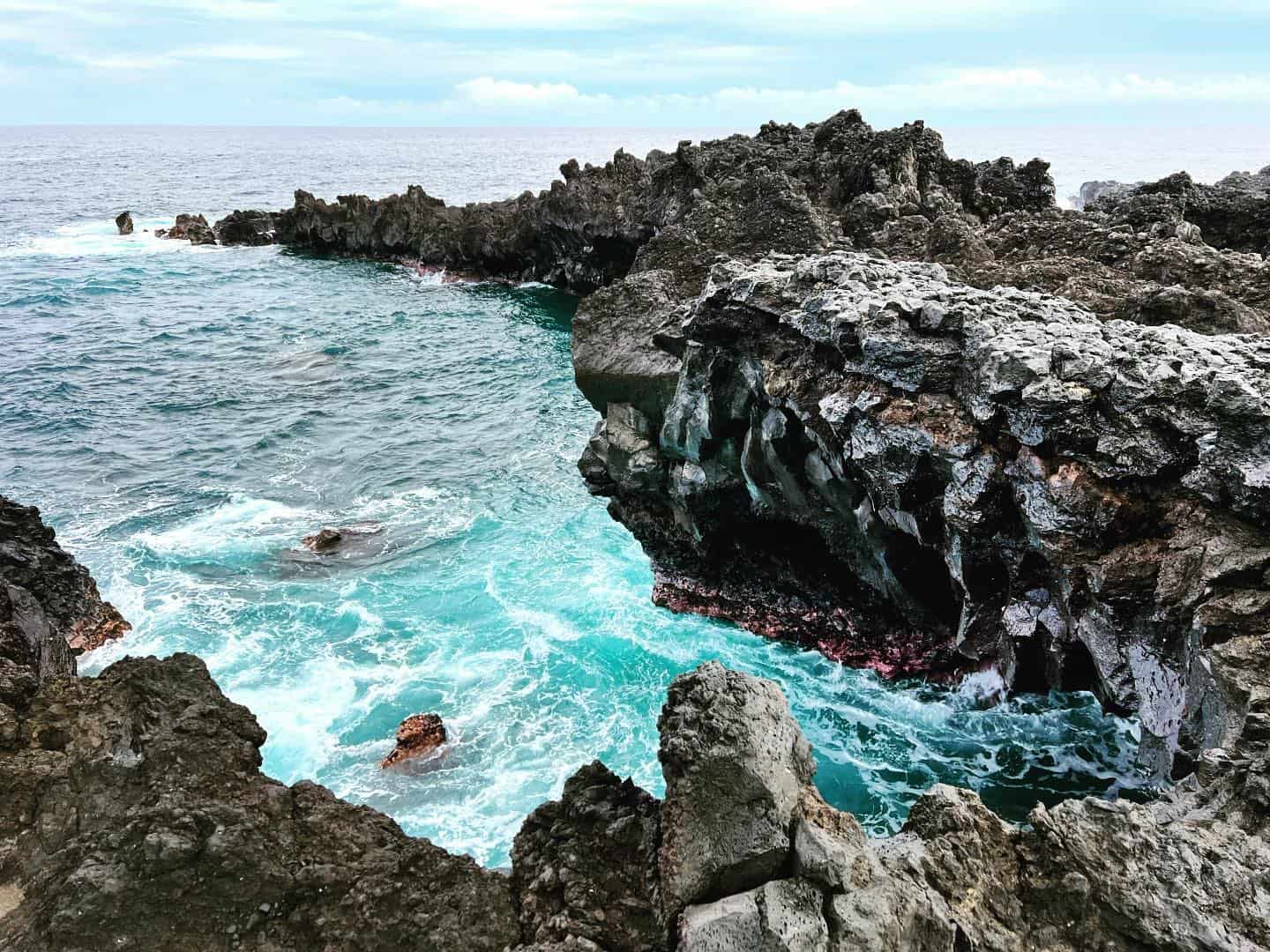Black lava sea caves and turquoise surf at Waianapanapa State Park on the Road to Hana in Maui, Hawaii