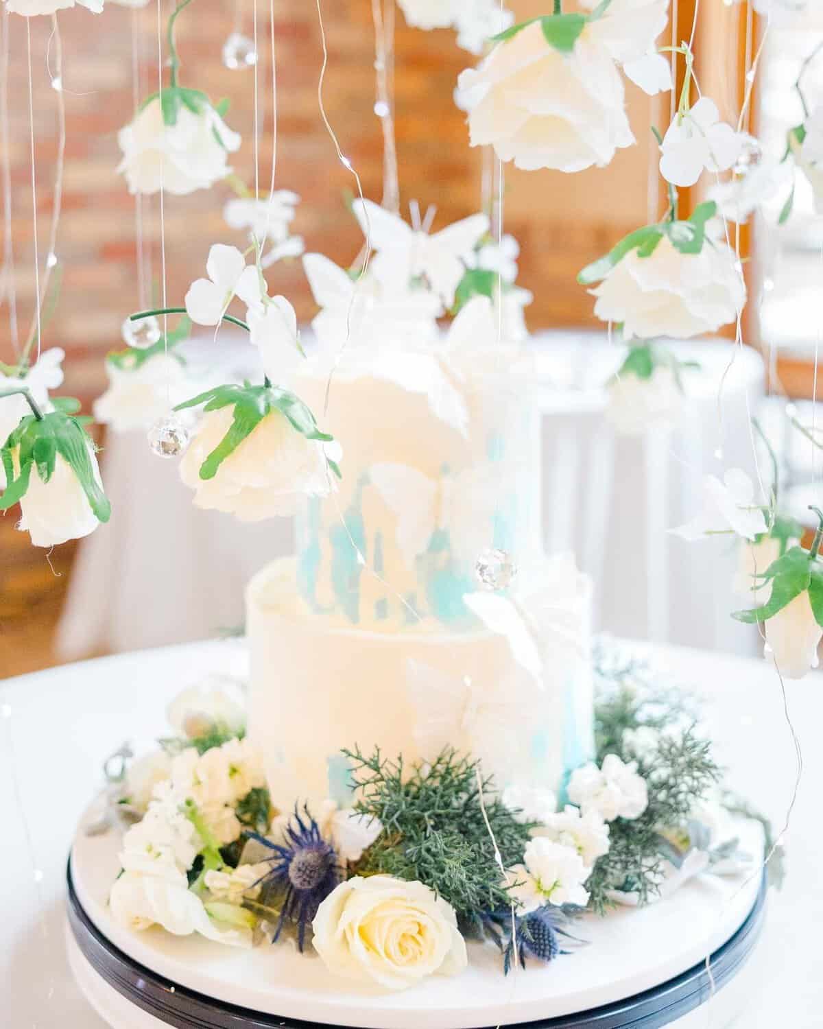 White gluten-free cake under hanging flowers at Sweet Gilly's
